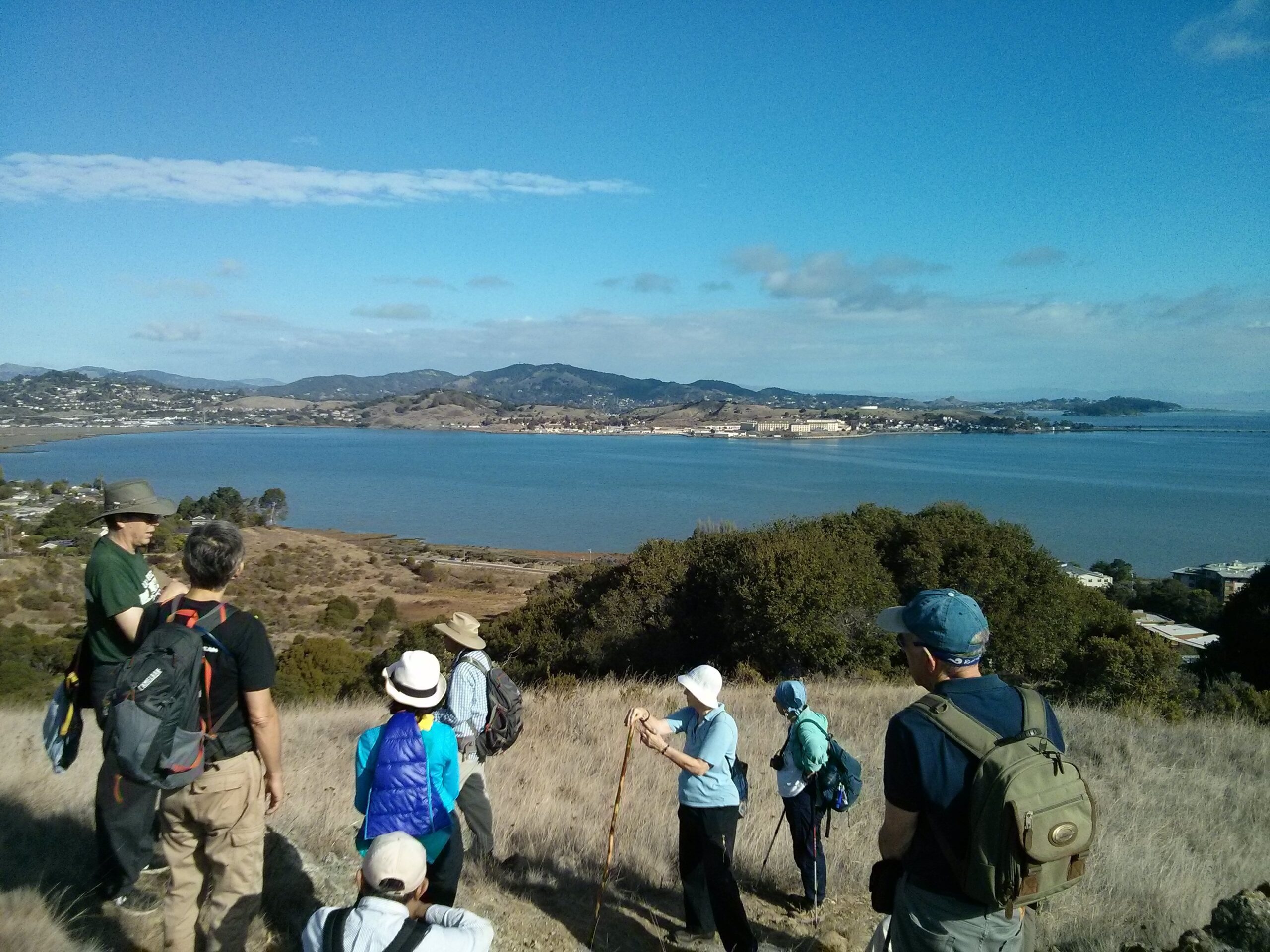 Photo showing a group of hikers looking out over the bay from a mountain