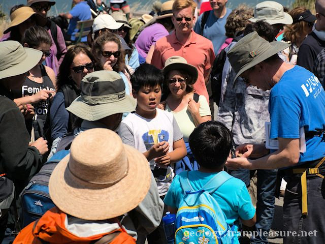 A group looking as a man talks, several kids in the group.
