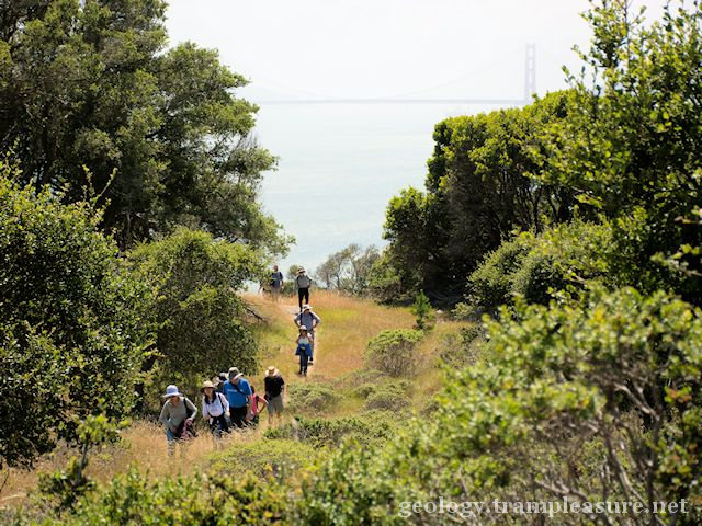 photo showing a group hiking along a trail with the Golden Gate Bridge int eh background